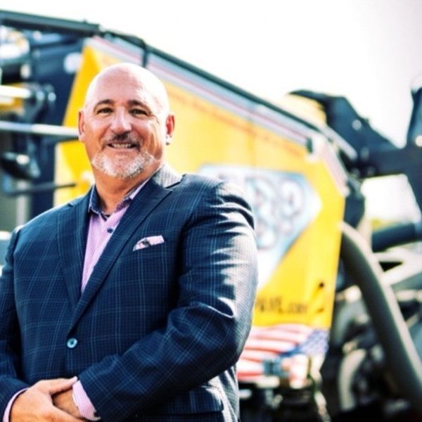 Tom Eosso in a suit in front of paving equipment