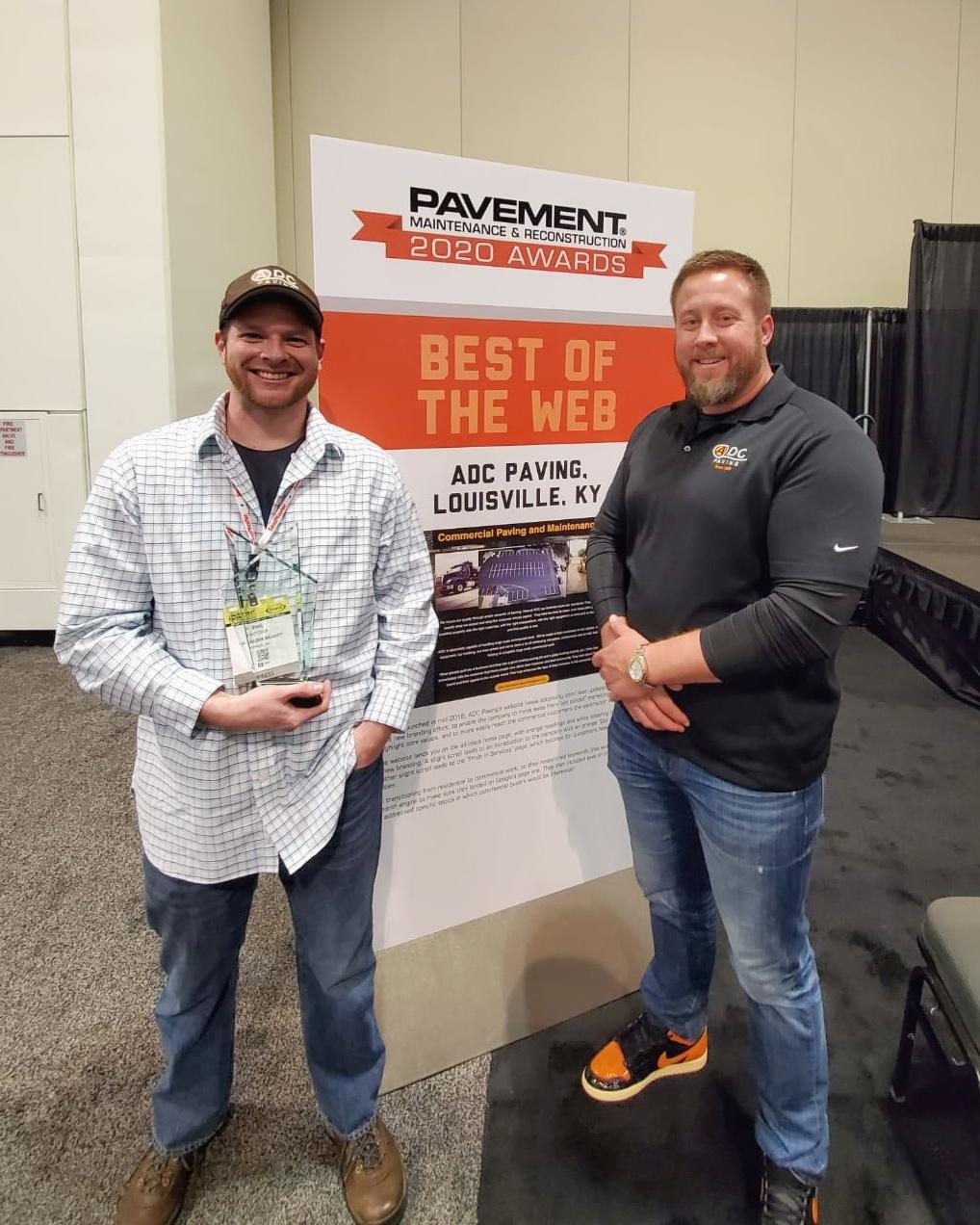 Phil Metzger holding a glass award beside Kevin Gray, in front of a Pavement Maintenance and Reconstruction 2020 Awards sign reading Best of the Web, ADC Paving, Louisville, KY