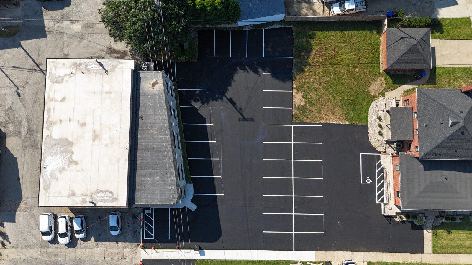 Top-down drone view of a freshly paved and striped commercial lot with an accessible space