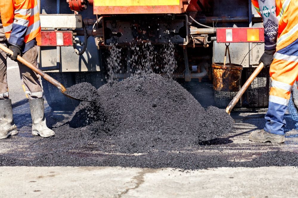 Paving crew working together behind a dump truck